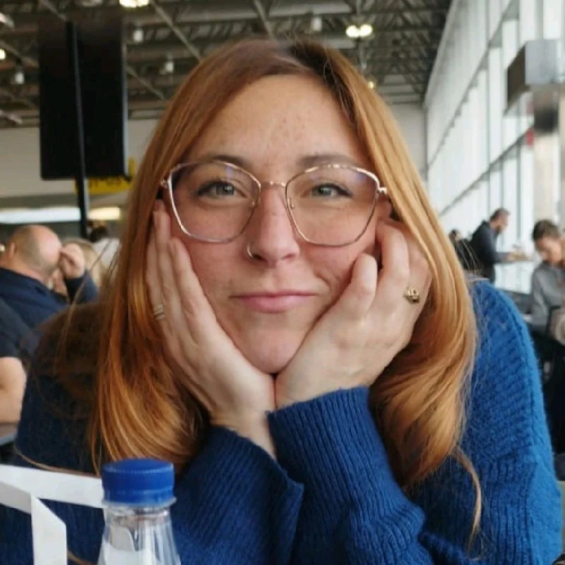 Ylenia Micci resting her chin on her hands, wearing glasses and a blue jumper